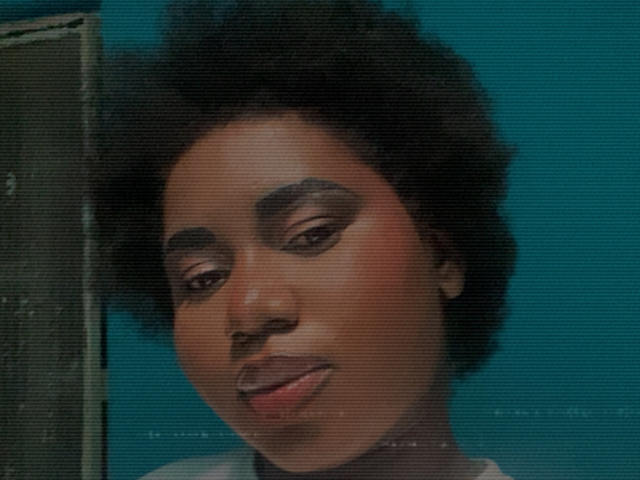 Close-up of Dilay with dark, curly hair against a teal background. Dilay has a medium brown skin tone, subtle pinkish lipstick, and thin, dark eyebrows. The image has a slightly grainy texture, with a vertical line on the left side. Dilay's expression is calm, with slightly parted lips. The focus is on Dilay's face, with the upper part of a gray shirt visible. The style is realistic, with a slight vintage film effect.
