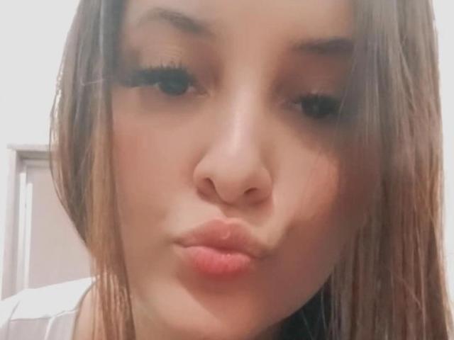 AngelyouAremine's pouty face with full lips, brown eyes, long eyelashes, and brown hair, making a kissing expression. Her nose is centered, and her skin is light.
