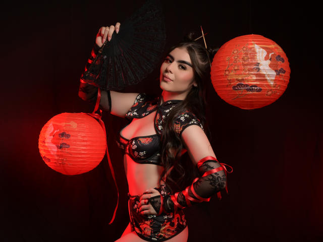 SofiaaFontaine with long brown hair, wearing black floral lingerie, holding a black fan, red lanterns, and red-lit background, showing her tits and ass, looking confident.