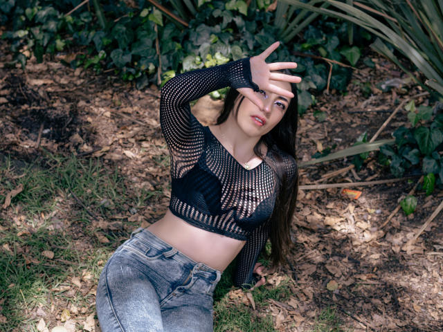 Ann Fisher ha lunghi capelli castani, indossa un top corto di rete nera che mette in mostra il seno, e jeans grigi consumati, è sdraiata sull'erba con un braccio alzato, che le copre gli occhi..