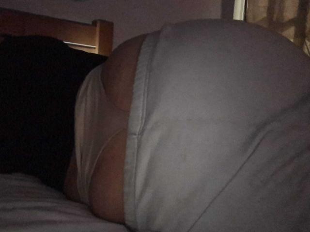 HanniRoss is lying on a bed, showing a large butt in white underwear, with the camera focused on her lower back and butt. The lighting is dim.