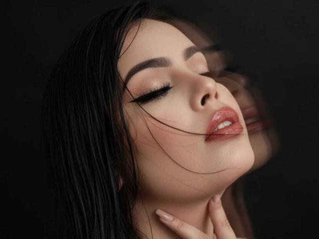 NathalyRose69's face is in the shot, eyes closed, black hair, glossy pink lips, and a slightly open mouth, with her hand gently touching her neck. Dark, blurred reflection.
