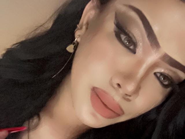 MissCuteBebe has glossy brown eyes, thick black eyebrows, and full pink lips. She's wearing a small gold heart earring with black hair. Her skin is fair and smooth.