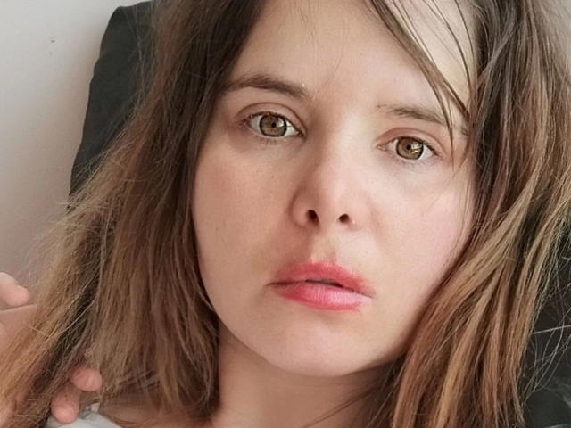 ElenaSchatz-hot has light brown eyes, slightly parted pink lips, and messy brown hair with blonde highlights, looking tired with a neutral expression.