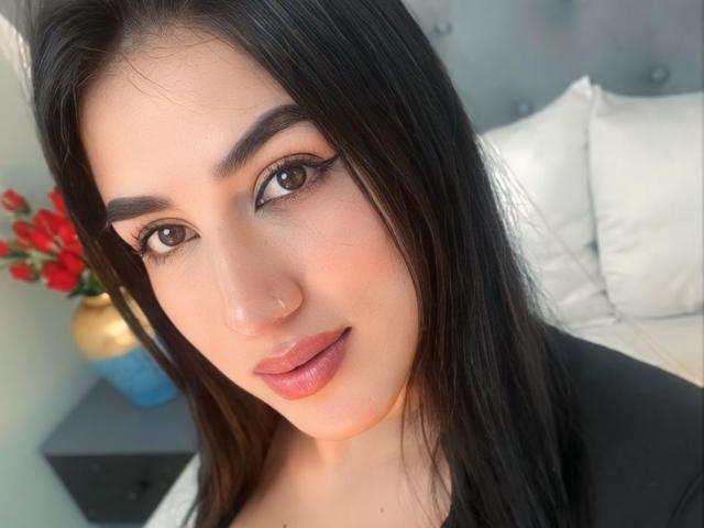 AlanaHarris has a cute face with dark brown eyes, full pink lips, and straight black hair, wearing a black top, showing her nose and slight smile.