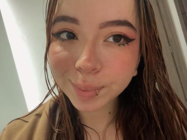KattyHards with wet brown hair, pouty lips, nose ring, and winged eyeliner, looking at the camera. She has fair skin and a small mole under her right eye.