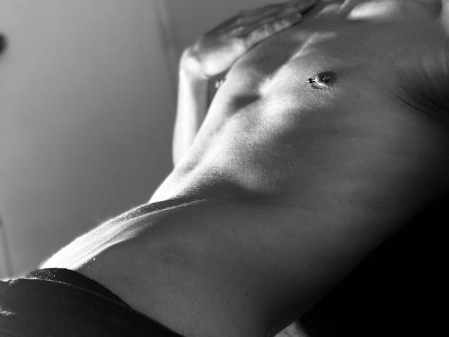 DeimHt's slim, toned, bare chest with small, hard nipples in a black-and-white shot, highlighting their smooth, muscular, light-skinned torso and subtle abdominal definition.