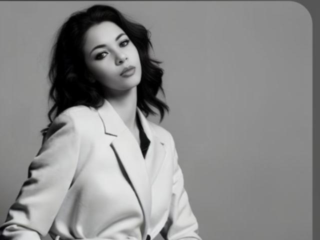 KarlaVip with wavy dark hair, wearing a white blazer, has a confident, slightly tilted head look, and a subtle, sexy smile. Her ass is not visible.
