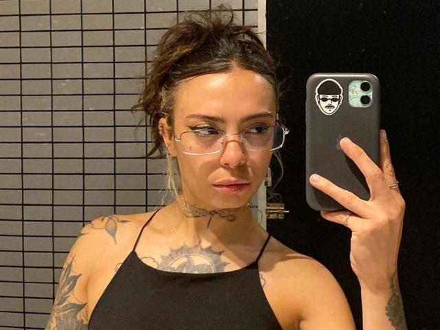LunaRoses-hot with glasses, nose ring, and tattoos, taking a selfie in a mirror. She's wearing a black halter top, and has her hair in a messy bun.