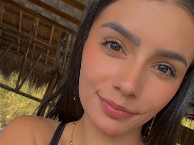 KimmyK tiene la piel morena, cejas oscuras, ojos marrones, cabello negro largo y una sonrisa sutil. Lleva una blusa negra con aretes dorados. Sus pechos son pequeños y visibles..