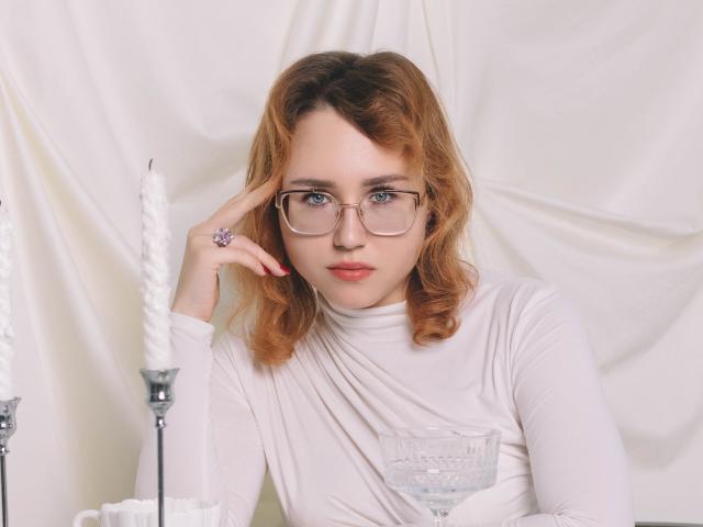 TeresaBirt with glasses, red hair, white dress, holding a glass, finger on temple, candle in background, looking serious, wearing a purple ring, soft light.