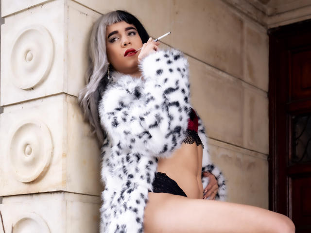 AliceCoolenk with gray hair, black lingerie, and white fur coat, smoking, leaning against a stone wall, showing her tits and black lace panties, looking sultry.
