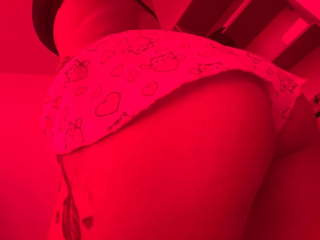 DamiAmbani's butt in white panties with a cute, cartoon-patterned design, illuminated by red lighting, showing her round, curvy ass from a low, side angle.