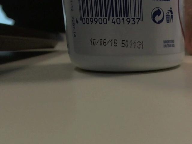 White plastic bottle with barcode, slightly visible lid, on a flat surface. The bottle's bottom is in focus, showing a smooth, shiny texture. FlipFlops-hot's hand is partially visible.