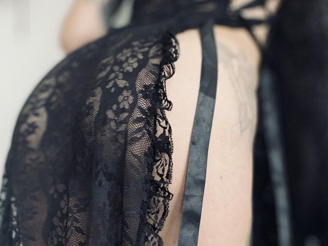 La lencería de encaje negro de DaneeSoHot muestra su trasero desnudo y tatuado, con tirantes visibles. Su trasero curvilíneo, cubierto de encaje, es el foco principal, resaltando su aspecto sexy y seductor..