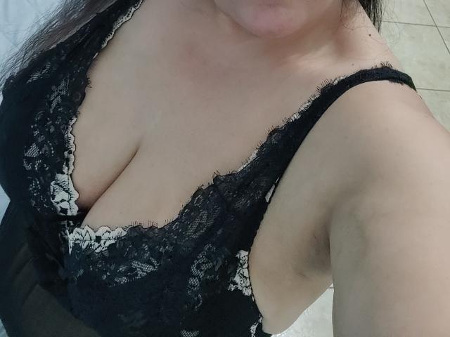 AnaPiyas' big, soft tits in a black lace bra with white lace trim, showing her cleavage and part of her chin. Her skin is light, and she has dark hair.