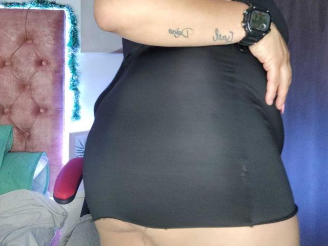 CristinaMendez's black dress hugs her curvy butt and slightly reveals her fat buttcheeks. She has a tattoo on her upper arm and wears a black watch.