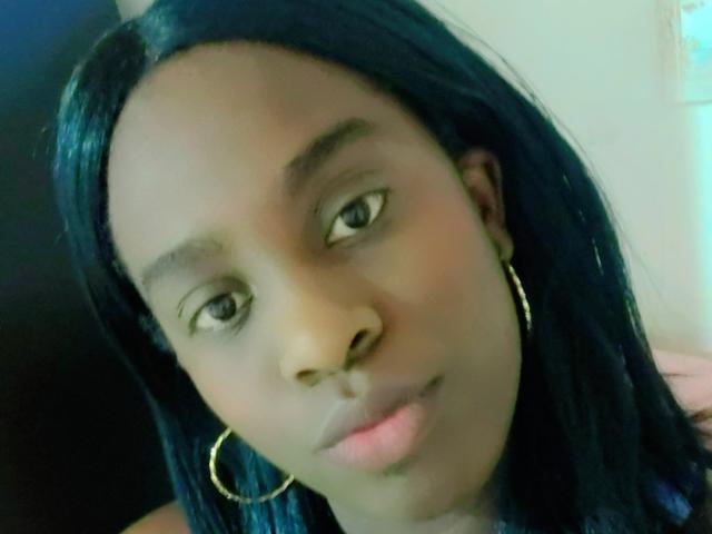 BlackKim with dark skin, straight black hair, and gold hoop earrings, has a neutral expression and slightly parted pink lips. Her eyebrows are thin and slightly arched.