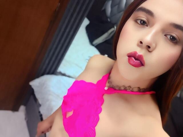 AndrewTaylor69 with pink lace bra, puffy red lips, choker, brown eyes, and straight brown hair, showing small tits and a light skin tone, looking up at the camera.