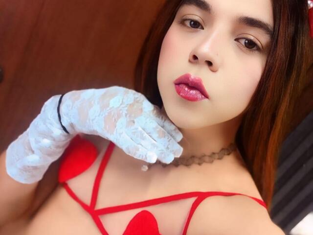 AndrewTaylor69 with red lingerie, white lace glove, pink lipstick, and brown hair, showing tits, wearing a choker, and looking at the camera.