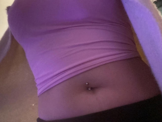 Melli-hot's pink top, showing her flat stomach with a pierced navel, and a hint of black pants. Boob outline visible, no other body parts shown.