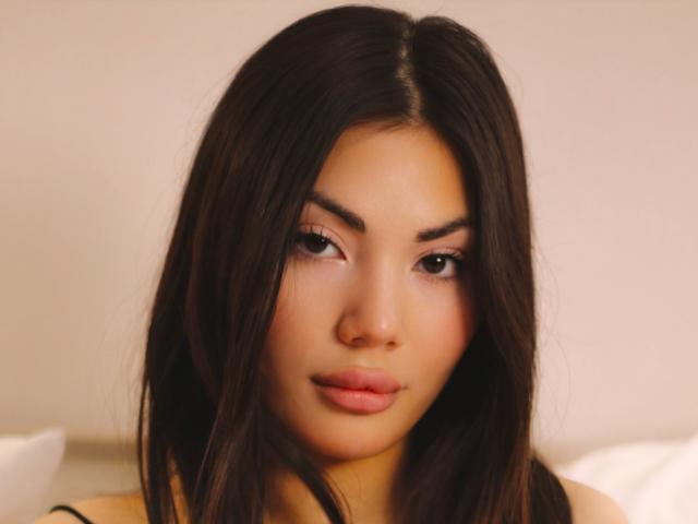 MonicaLuxe heeft donker, steil haar, volle wenkbrauwen, bruine ogen en roze lippen. Ze kijkt naar beneden met een enigszins serieuze uitdrukking. Haar gebruinde huid is glad en egaal..