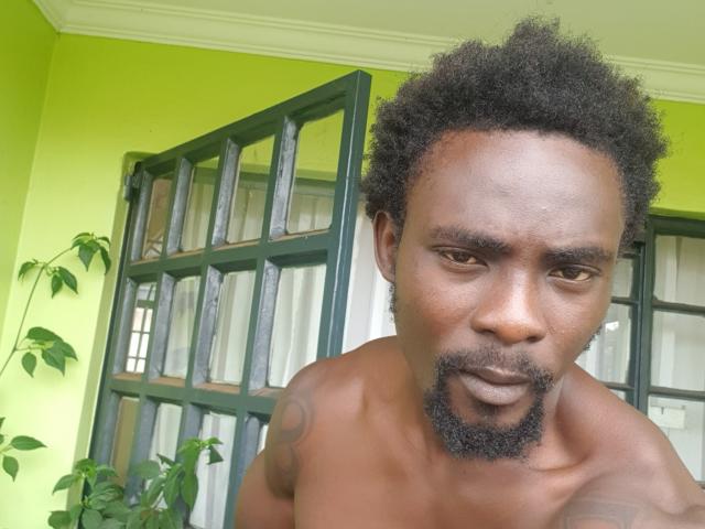 TheBlackStallionn, shirtless with a curly afro and goatee, has a tattoo on his right shoulder, and is looking directly at the camera with a serious expression.