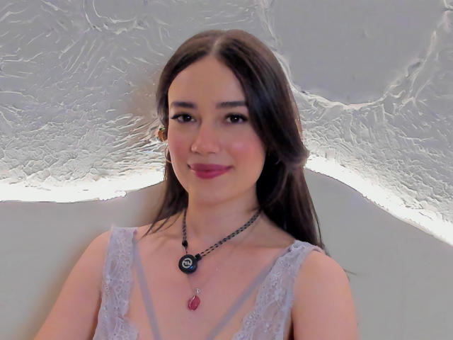 MariaLoft ha lunghi capelli castani, pelle chiara, rossetto rosa e un sorriso carino. Indossa una camicetta in pizzo, una collana nera e un ciondolo rosso, con piccoli orecchini..