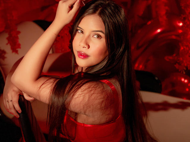 Ahriy with long brown hair, red lipstick, and red dress, looking over her shoulder, hand in hair, showing her tits and ass, red background, sexy, confident expression.