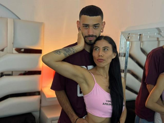 TashaAndRolo with her arm around Rolo's neck, she's wearing a pink sports bra, showing her tits, and he's in a maroon t-shirt with a tattoo on his arm.