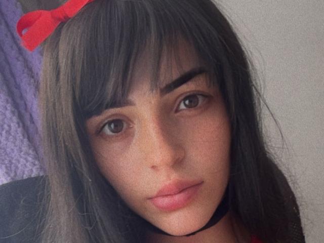 Liiil ha lunghi capelli castani con un fiocco rosso, sopracciglia scure, occhi marroni e labbra rosa. Indossa una collana nera e sembra leggermente annoiata, con un'espressione appena accennata..