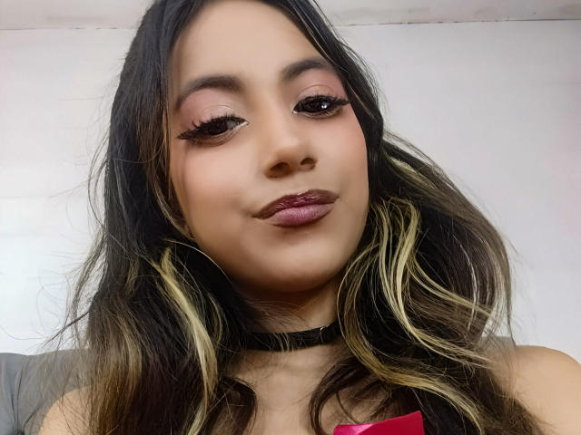 KarlaMiilan heeft donkere ogen, lang golvend bruin haar met blonde highlights, en draagt roze oogschaduw, dikke wimpers en donkerpaarse lippenstift, met een zwarte choker..