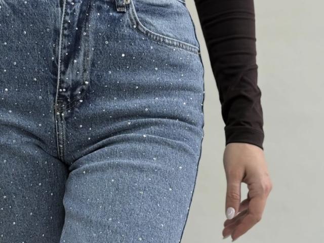 GlariyaHot's blue, sparkly, tight jeans, showing a big, curvy butt, with a black long-sleeve shirt, and a hand with white nails, right side of the frame.