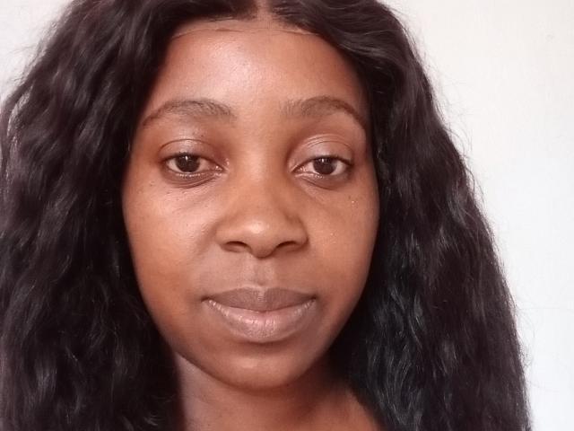 LindaSteph has dark brown eyes, wavy black hair, and a subtle smile. Her brown skin has a smooth texture, and her lips are naturally glossy.