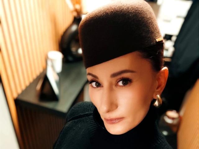 DesiredMistress-hot with a brown updo, wearing a black turtleneck, gold hoop earrings, and a black beret, has a sexy, cute face and brown eyes, looking at the camera.
