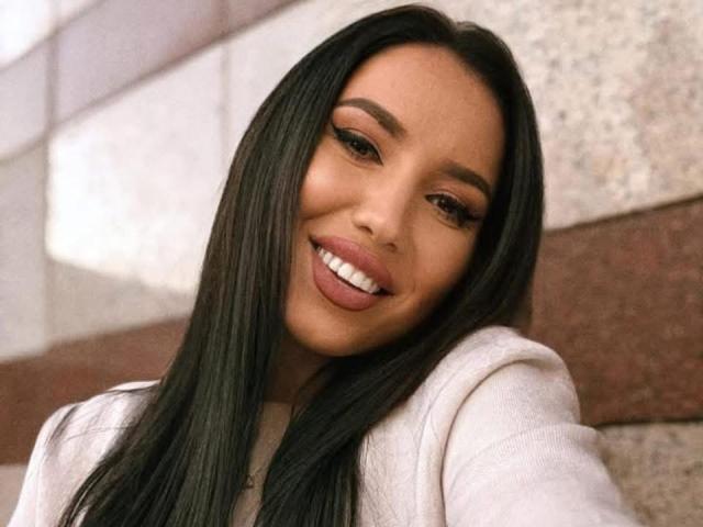 ArryaBlack has long black hair, brown eyes, and is smiling with her tongue slightly out. She's wearing a white sweater and has a cute, sexy look.