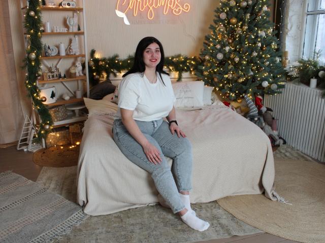 ScarletCargo with medium tits, white shirt, gray high-waisted pants, white socks, sitting on bed, smiling, dark hair, Christmas tree with lights, neon sign, cozy room, daytime.