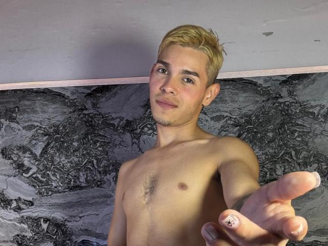 SmileKai, shirtless with blond hair, smiling at camera, pointing forward with right hand, light skin, small chest, slight body hair, relaxed, confident, cute.