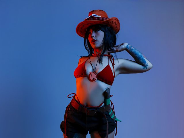 CarlaMiceli with black hair, red cowboy hat, red bikini top, brown shorts, tattooed arm, blue and orange lighting, hand in hair, showing tits, flat stomach, belt with pouches.