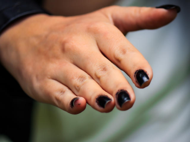 JessyLuxs' hand with black glossy nail polish, fingers slightly spread, showing natural skin tone and subtle texture. Boobs aren't visible, just the hand.