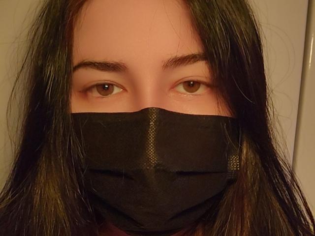 Lanarei, avec ses yeux marron, un masque noir recouvrant son nez et sa bouche, de longs cheveux bruns foncés et des sourcils légèrement arqués. Un tissu noir transparent est visible au-dessus de sa bouche..