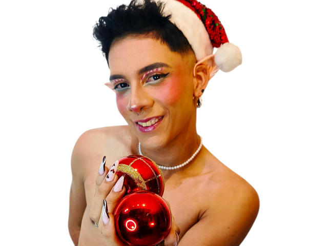 BlakeNoir with short black hair, wearing a Santa hat, holding red Christmas ornaments, smiling, pearl necklace, and painted nails, bare shoulders, white background.