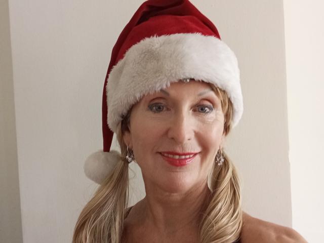 ElizaWendy with blonde pigtails, wearing a red Santa hat with white fur, red lipstick, smiling, showing her tits slightly, wearing sparkly earrings, and blue eyes.