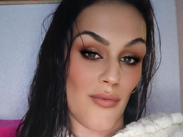 Sarayy69 has dark wet hair, brown eyes with heavy eyeliner, full pinkish-brown lips, and a small nose ring. Her makeup is bold, with defined eyebrows and subtle blush.