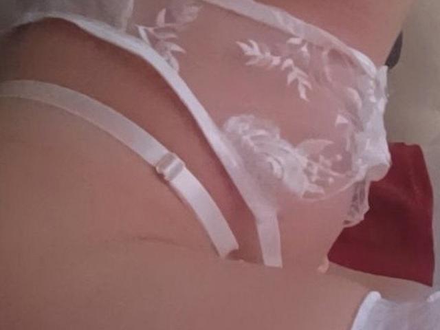 SugaryCarrie's white lace panties with floral embroidery, showing her ass and thigh, have a strap on the side, and the fabric is sheer.