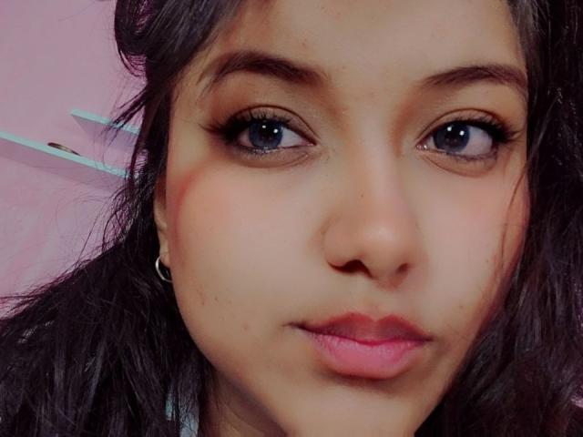 AzulMoon's face with dark brown eyes, full pink lips, and slightly wavy black hair. She has a small nose ring and subtle makeup. Her skin is light brown.