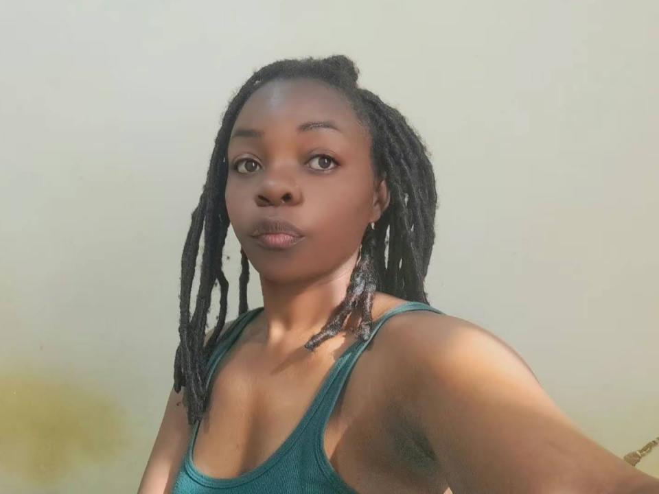 CandyBalbe has dark brown skin, small round tits, and long black dreadlocks. She's wearing a teal tank top, looking at the camera with a neutral expression.