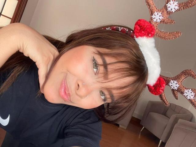 ChloeVixen mit braunen Haaren, Pony und einem niedlichen Nasenpiercing, trägt einen Rentier-Haarreif mit glitzernden Geweihen, lächelt und trägt ein schwarzes Nike-Shirt..