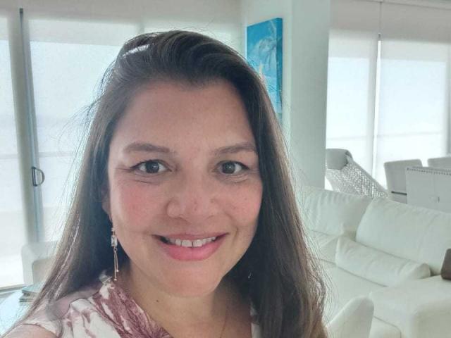 EstelaHot has medium-length brown hair, a cute smile with pink lipstick, and is wearing a pink and white lace top. She has small tits and is in a bright room.