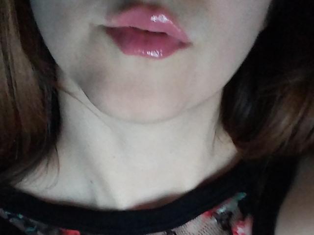 ImFireMoon's glossy pink lips, slightly parted, showing a hint of her pale neck and black lace top with red floral pattern. Her brown hair is partially visible.